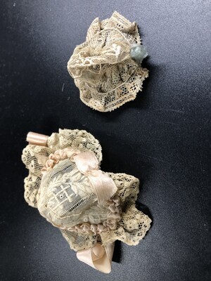 1a06b1f9-0e25-477a-8a3c-5583c9cc46d5.jpg; 1960-0274-KPO/050; 2 crème kleurige, kanten bonnetten met roze en blauwe accenten; mutsen