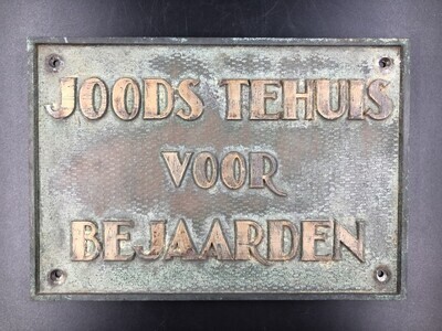3174cfb0-f1f0-4e7f-926a-ce97261bd055.jpg; 1981-0037-HHI; Bronzen rechthoekige plaquette, met in relief opschrift: JOODS TEHUIS VOOR BEJAARDEN.; naamplaten