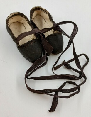 cec81594-a801-41b6-b4f3-5b0b5b08dc75.jpg; 1960-0168-KPO/a-b; Een paar zwart satijnen schoenen met striklinten.; poppenkleding