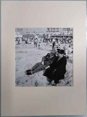 fe989b68-dd53-4344-a835-ec9ff9bb8ae6.jpg; 0000-0896-PRE; Ouder echtpaar in 'zondagse' kledij op de voorgrond van een vol strand.; fotografie